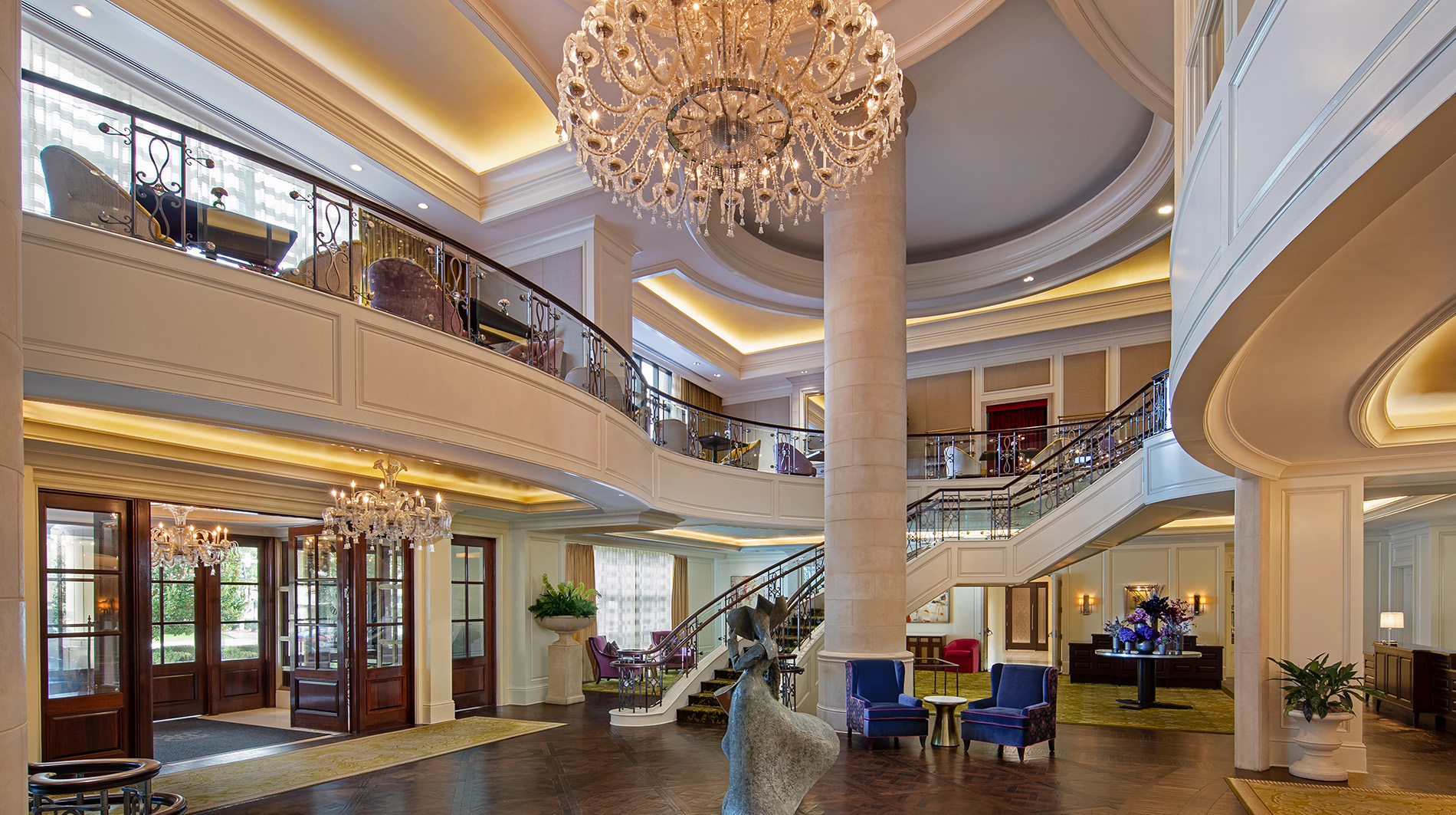 The St Regis Atlanta | The Luxury Travel Atlas Luxurious Hotel Lobby with a Crystal Chandelier, Curved Mezzanine, and Marble Columns.