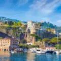 Harbor View of a Mediterranean Town with Boats Docked Along a Rocky Waterfront and Hillside Homes.