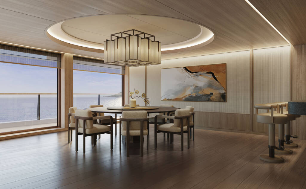 Elegant dining room with a round table, beige upholstered chairs, and a geometric pendant chandelier, overlooking the sea through large windows.