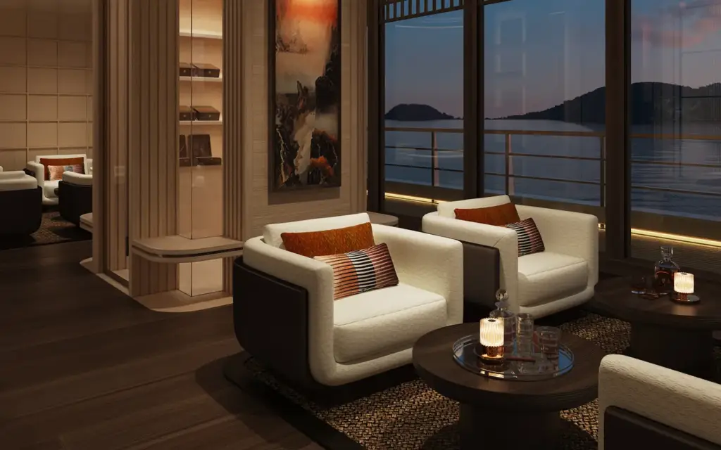Amangati cigar lounge 03 1394x1394px | The Luxury Travel Atlas | The Luxury Travel Atlas Luxurious Hotel Lounge with Cream Armchairs, Orange Cushions, and Round Coffee Tables by Windows Overlooking a Sunset Water View.
