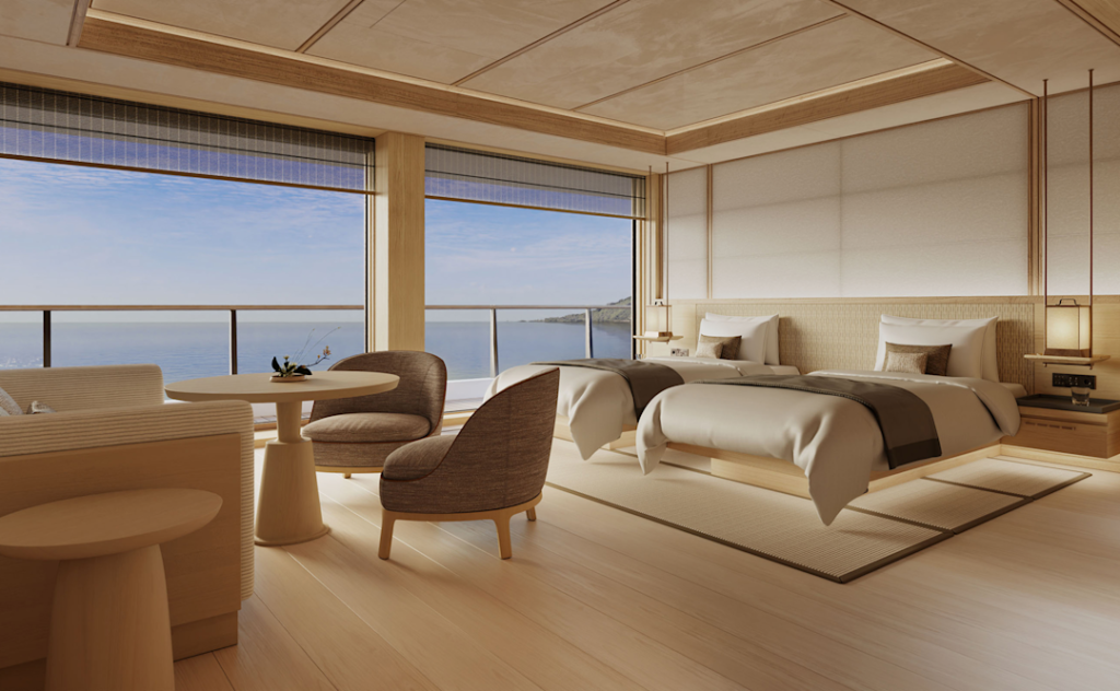 Spacious hotel room with two neatly made beds, a seating area, and an ocean-view balcony windowed by floor-to-ceiling glass doors.