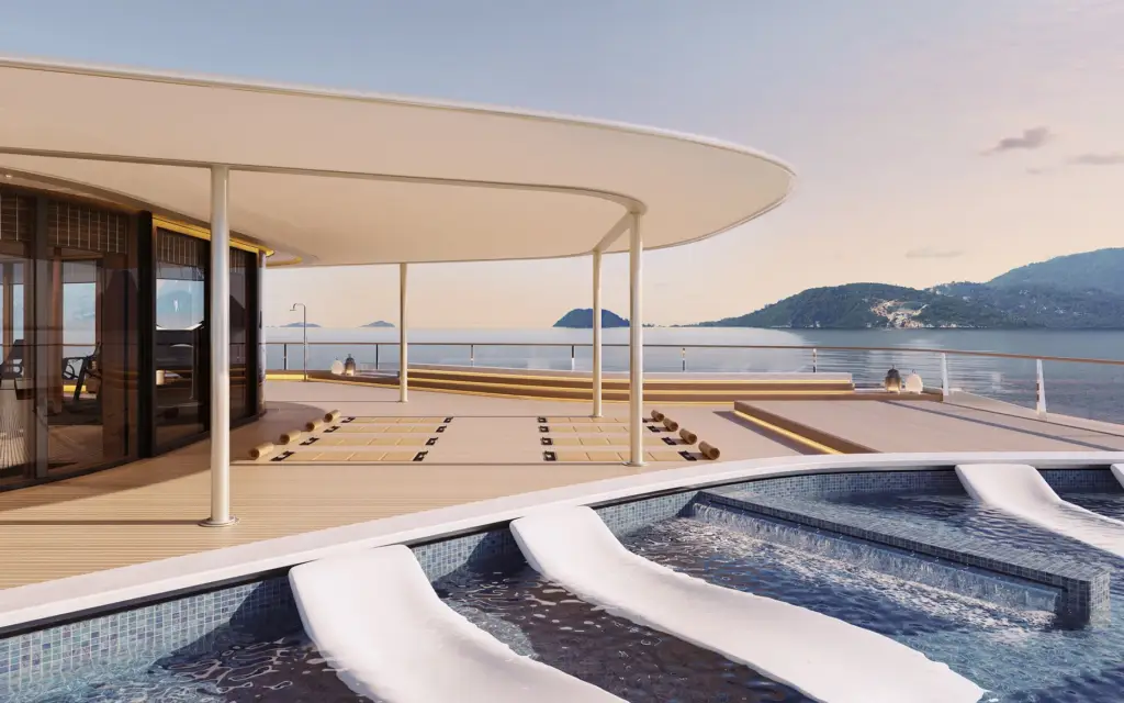 Amangati fitness studio exterior 01 1890x1167px | The Luxury Travel Atlas | The Luxury Travel Atlas Luxurious Outdoor Pool Deck on a Yacht with Curved White Canopy, Sun Loungers, and a Calm Sea with Distant Hills.