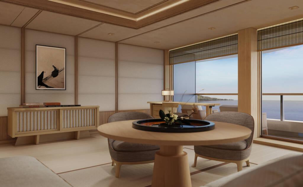 Ocean-view living room with round wooden table, soft seating, and beige-tiled floors in a minimalist Japanese-inspired space overlooking the sea.