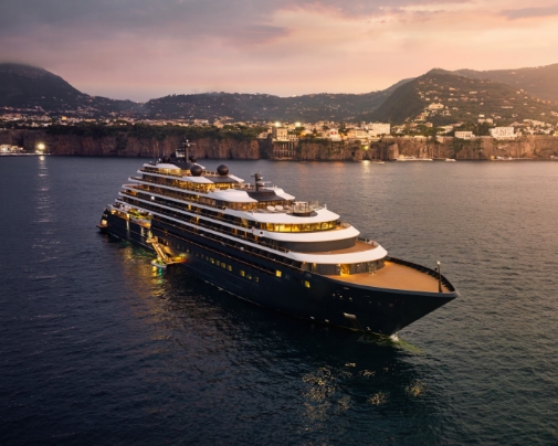 Large Luxury Yacht on Calm Water Near a Coastal Town at Sunset.