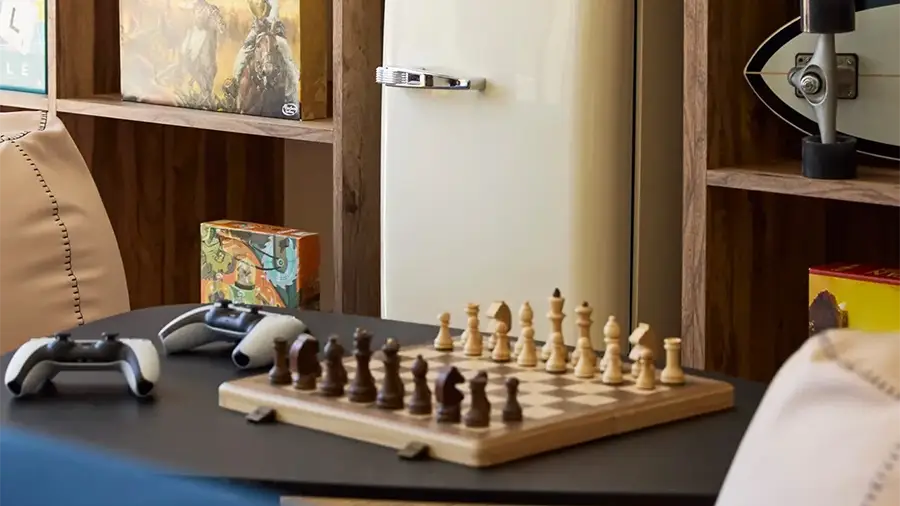 Chessboard with White and Dark Pieces Mid-game on a Table, a Game Controller Nearby on the Left Side.