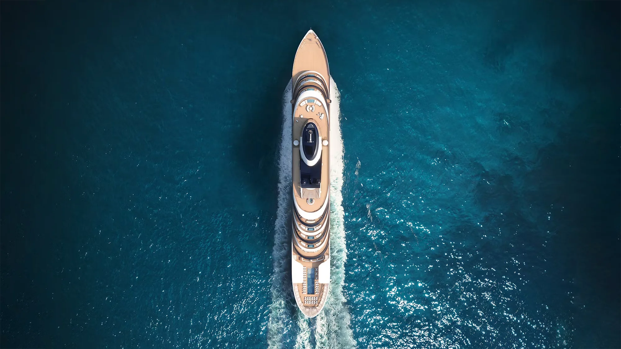 Aerial view of a luxury yacht speeding through turquoise sea.