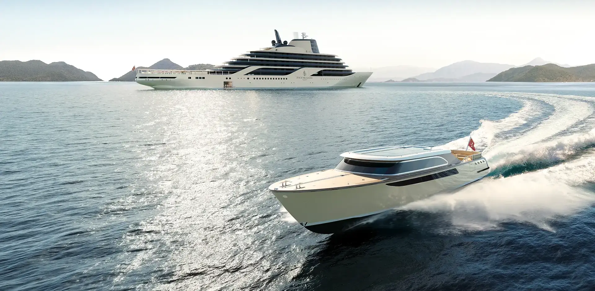 Two luxury yachts glide on calm blue water with a mountainous coastline in the distance.