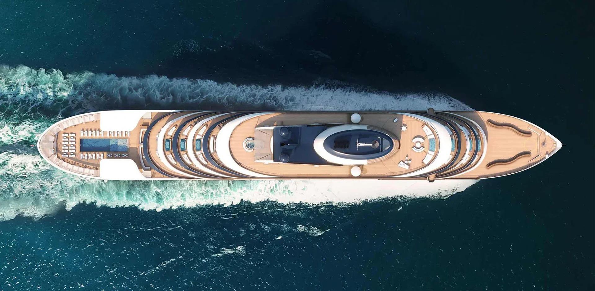 Aerial top-down view of a large luxury motor yacht cruising through turquoise sea with multiple decks and sun loungers on the aft deck.