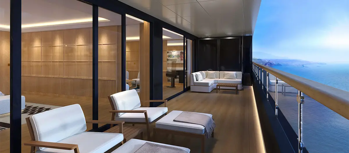 Luxurious outdoor balcony lounge with white cushioned chairs and a sofa, overlooking the sea.
