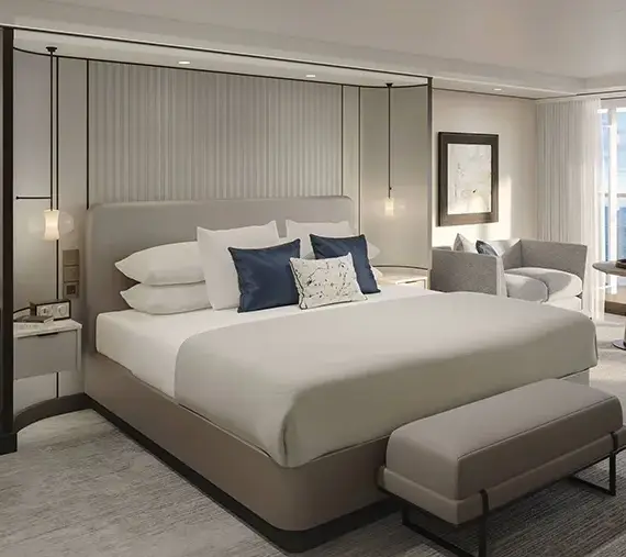 Luxurious Hotel Room with a King Bed, Seating Area, and an Ocean-view Balcony Beyond the Windows.