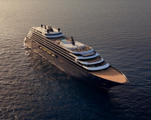 a Large Luxury Cruise Ship Sails on Calm Open Water, Viewed from Above, with Multiple White Decks and Sun Decks on a Dark Hull.