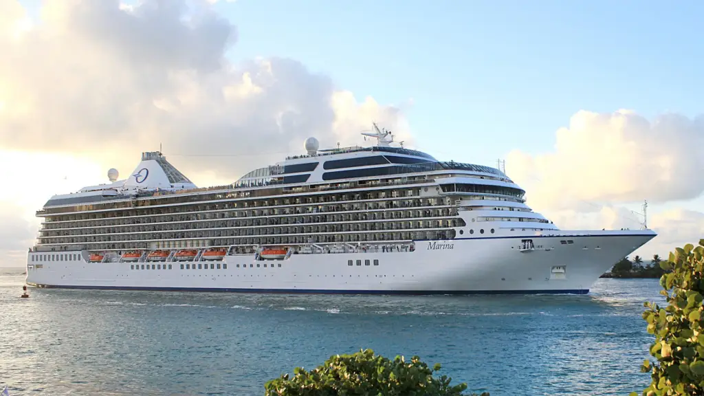 Large white cruise ship named Marina on calm water with a blue sky and clouds in the background.