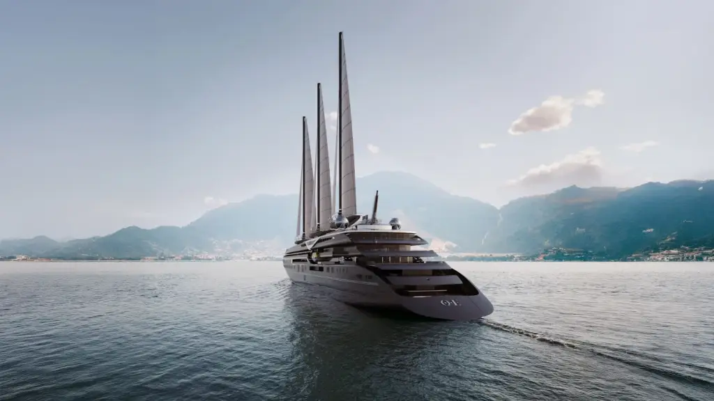 Luxurious multi-masted yacht cruising on calm sea near a mountainous coastline.