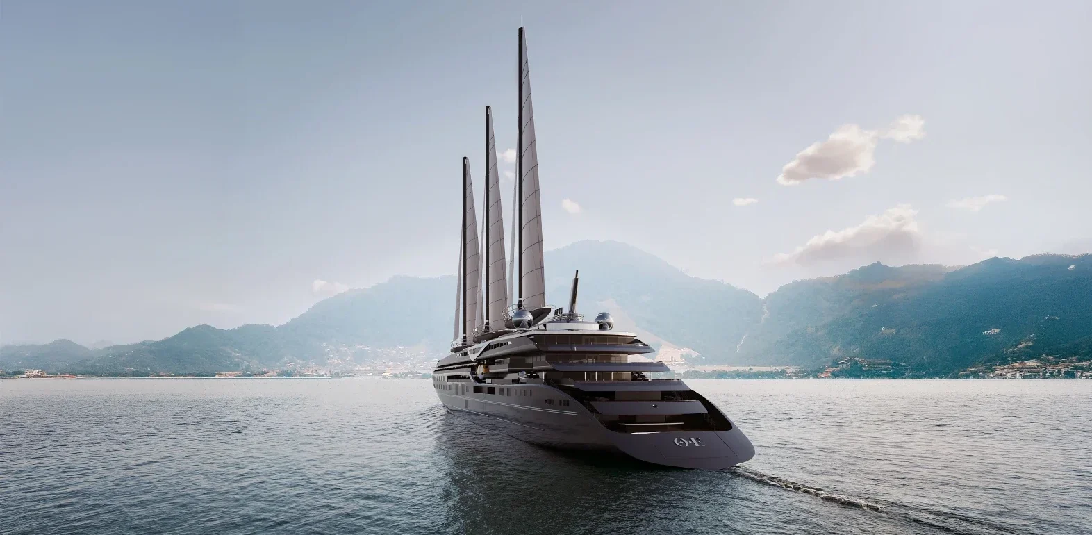 Large luxury yacht with four tall sails gliding on calm sea, with a mountainous coastline in the background.