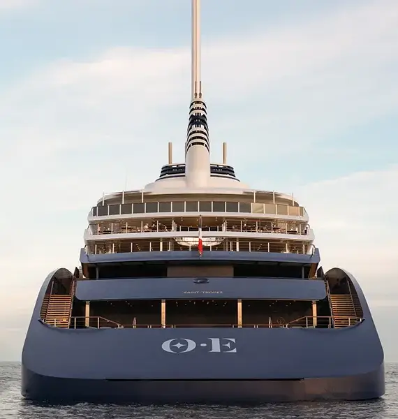 Orient Express Yachts Feature 03 | The Luxury Travel Atlas Rear View of a Large Multi-deck Luxury Yacht on Calm Sea, Blue Hull, Spacious Open Aft Decks, Tall Radar Mast Against a Pastel Sky.