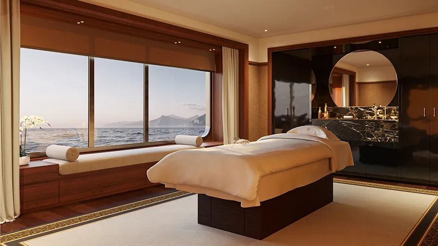 Orientexpress sailingyachts corinthian le spa byguerlain | The Luxury Travel Atlas | The Luxury Travel Atlas Luxurious Spa Treatment Room with a Massage Bed, Large Ocean-view Windows, and a Round Mirror Above a Marble Counter.