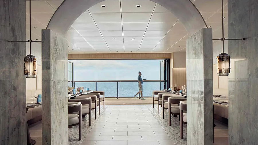 Elegant Restaurant Interior with Marble Pillars, Tables Set for Service, Open to an Ocean-view Balcony; a Person Walks Outside.