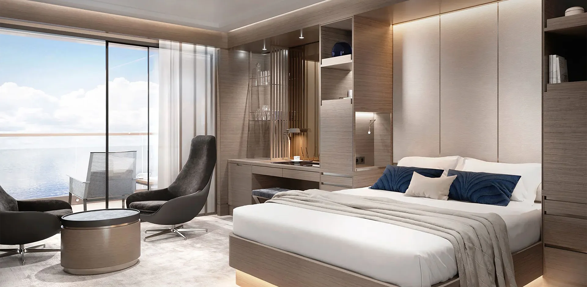 Contemporary hotel room with a king bed, blue pillows, and wood-panelled cabinetry overlooking a sea-view balcony.