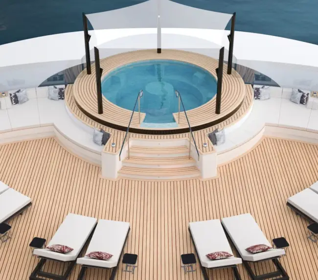 Aerial View of a Circular Hot Tub on a Luxury Yacht Deck, Surrounded by White Seating and Wooden Loungers with Cushions and Pillows.